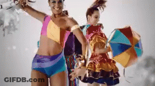 A Woman In A Bikini Stands Next To Another Woman In A Colorful Dress GIF