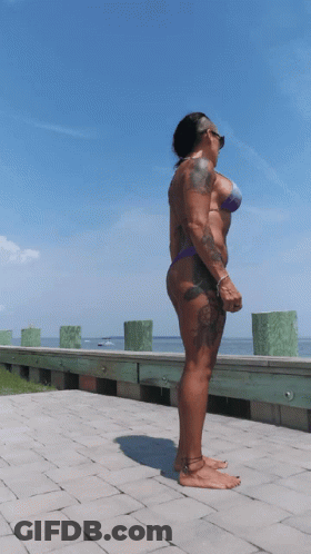 A Woman In A Bikini Stands On A Brick Walkway GIF
