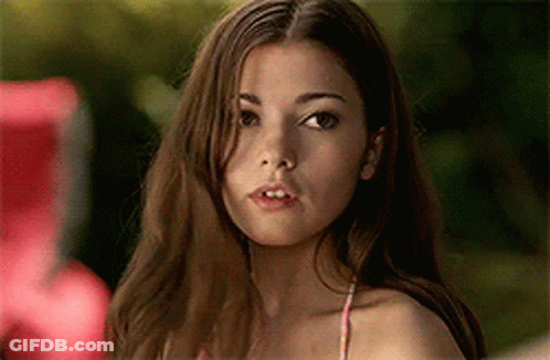 A Woman In A Bikini Top Is Looking At The Camera With A Serious Look On Her Face . GIF