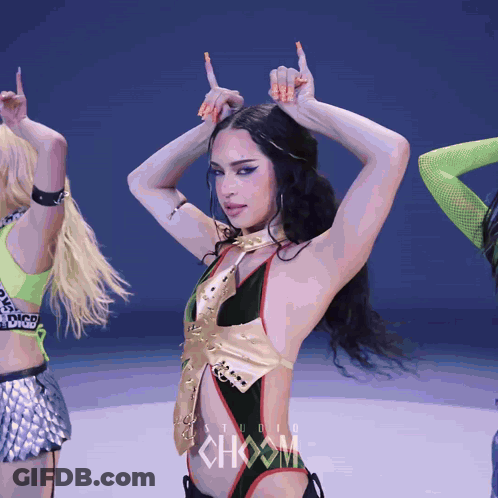 A Woman In A Black And Gold Bodysuit Is Dancing In Front Of A Sign That Says Choom GIF