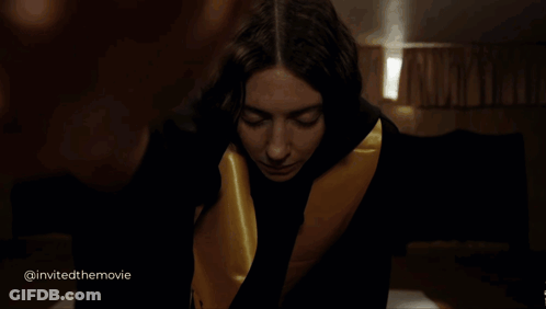 A Woman In A Black And Gold Robe Is Looking At The Camera With The Words Invited The Movie Below Her GIF