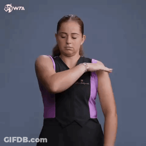 A Woman In A Black And Purple Dress Is Holding Her Arm . GIF
