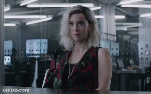 A Woman In A Black And Red Dress Is Sitting At A Table GIF