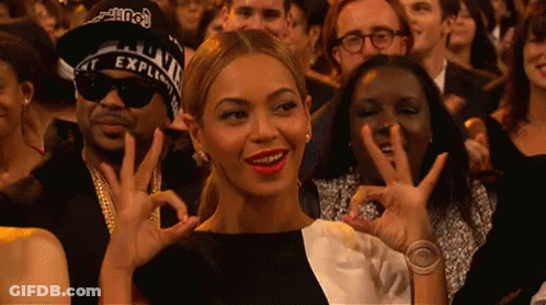 A Woman In A Black And White Dress Is Making An Ok Sign With Her Hands GIF