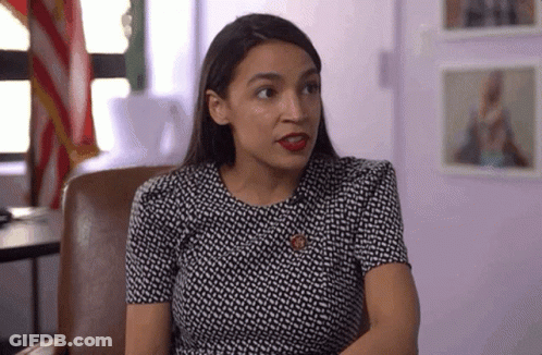 A Woman In A Black And White Dress Is Sitting In A Chair And Looking At The Camera . GIF