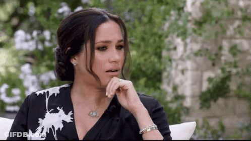 A Woman In A Black And White Dress Is Sitting On A Couch . GIF