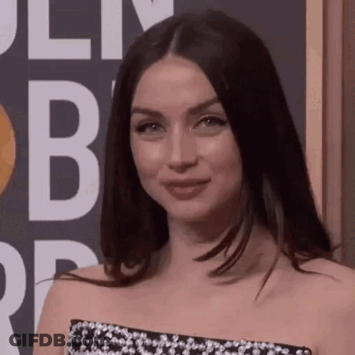 A Woman In A Black And White Dress Is Standing In Front Of A Sign That Says ' B ' On It . GIF