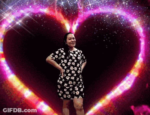Woman In Floral Dress In Front Of Pink Heart GIF