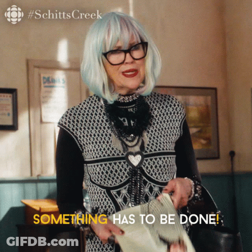 A Woman In A Black And White Outfit Is Holding A Newspaper And Says Something Has To Be Done GIF