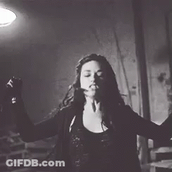 A Woman In A Black And White Photo Is Dancing In A Dark Room . GIF