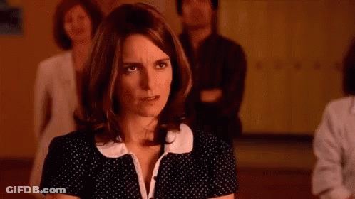 A Woman In A Black And White Polka Dot Dress Is Standing In A Room With Other People . GIF