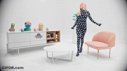 A Woman In A Black And White Polka Dot Outfit Stands In Front Of A Muppet Show Display GIF