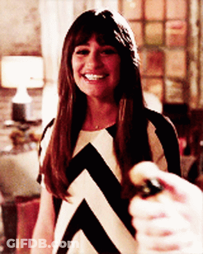 A Woman In A Black And White Striped Dress Smiles While Holding A Bottle GIF