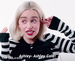 A Woman In A Black And White Striped Sweater Is Covering Her Ears With Her Hand . GIF