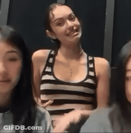 A Woman In A Black And White Striped Tank Top Is Smiling While Sitting Next To Two Other Women . GIF