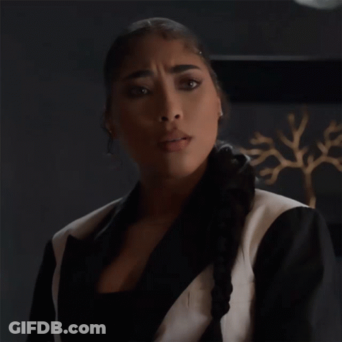 A Woman In A Black And White Suit Is Making An Okay Gesture GIF