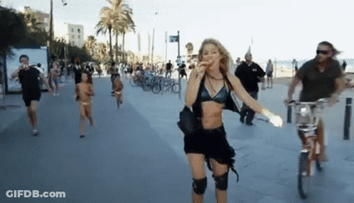A Woman In A Black Bikini Is Walking Down A Sidewalk GIF