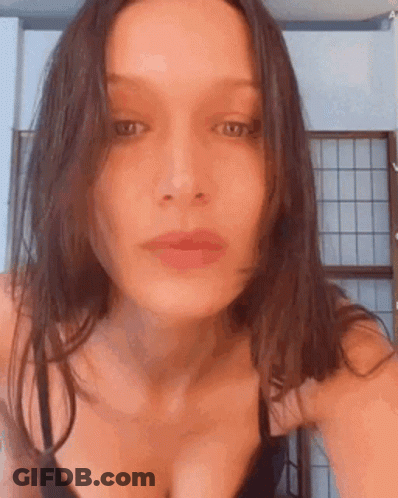 A Woman In A Black Bra Is Taking A Selfie In Front Of A Window . GIF