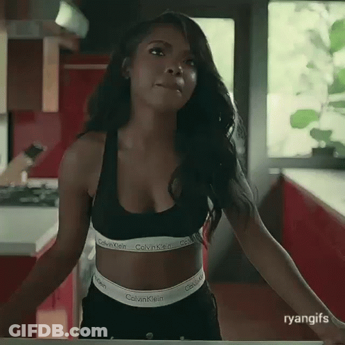 A Woman In A Black Calvin Klein Bra And Black Shorts Is Standing In A Kitchen . GIF