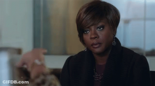 A Woman In A Black Coat And Earrings Is Sitting At A Table With A Man . GIF