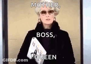 A Woman In A Black Coat And Sunglasses Is Holding A Magazine And A Laptop . GIF