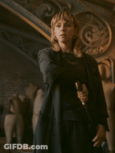 A Woman In A Black Coat Holds A Sword In Her Hand GIF