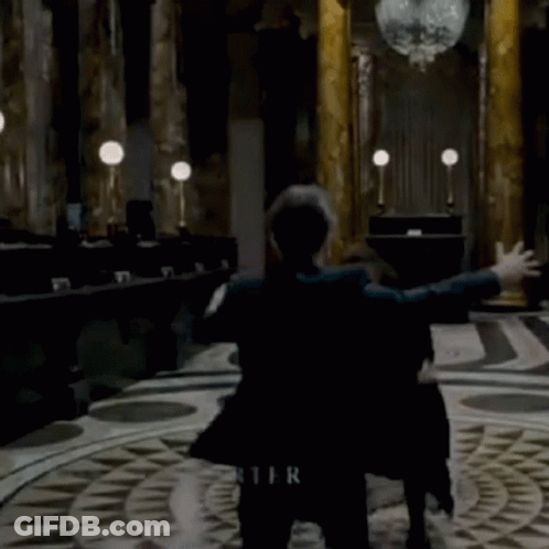 A Woman In A Black Coat Is Dancing In A Room With The Name Bonham Carter Written On The Floor GIF