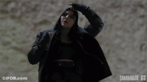 A Woman In A Black Coat Is Holding Her Hair In A Ponytail .. GIF