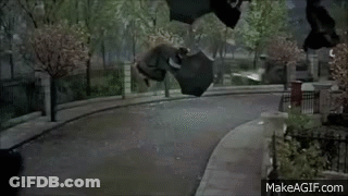 A Woman In A Black Coat Is Walking Down A Sidewalk . GIF