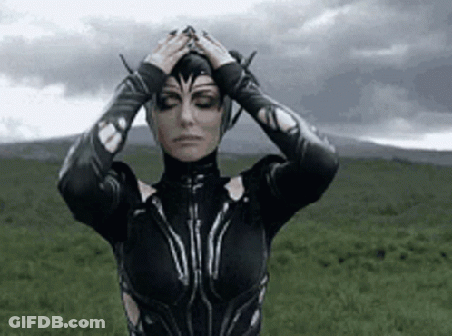 A Woman In A Black Costume Is Standing In A Field With Her Eyes Closed . GIF