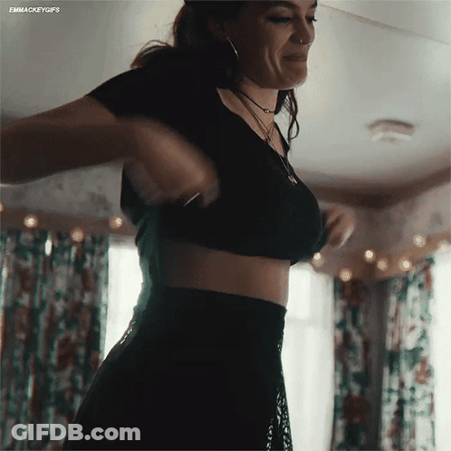 A Woman In A Black Crop Top And Black Skirt Is Standing In A Room GIF