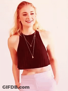 A Woman In A Black Crop Top And White Pants Smiles GIF