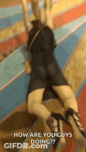 A Woman In A Black Dress And High Heels Is Laying On The Floor And Asking How Are You Guys Doing ? GIF