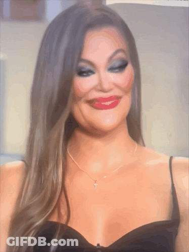 A Woman In A Black Dress Has A Cross Necklace GIF