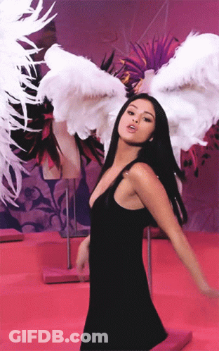A Woman In A Black Dress Has White Feathered Wings On Her Head GIF