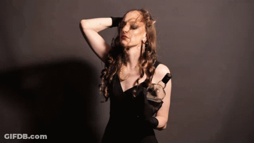 A Woman In A Black Dress Holding A Bottle Of Wine GIF