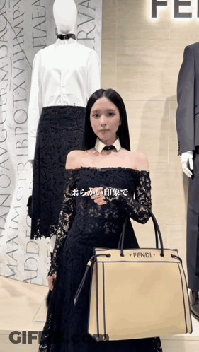 A Woman In A Black Dress Holding A Fendi Bag GIF