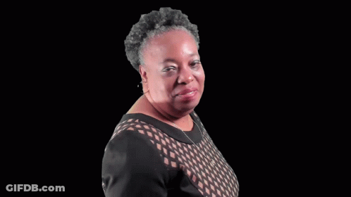 A Woman In A Black Dress Is Blowing A Kiss To The Camera . GIF