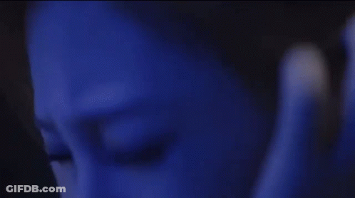 A Woman In A Black Dress Is Covering Her Ears In A Dark Room With A Monster In The Background . GIF