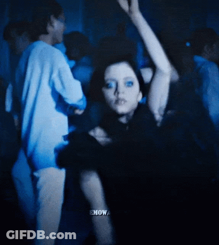 A Woman In A Black Dress Is Dancing In A Crowd With The Word Emow Visible GIF