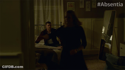 A Woman In A Black Dress Is Dancing In A Dark Room With #Absentia Written On The Bottom GIF