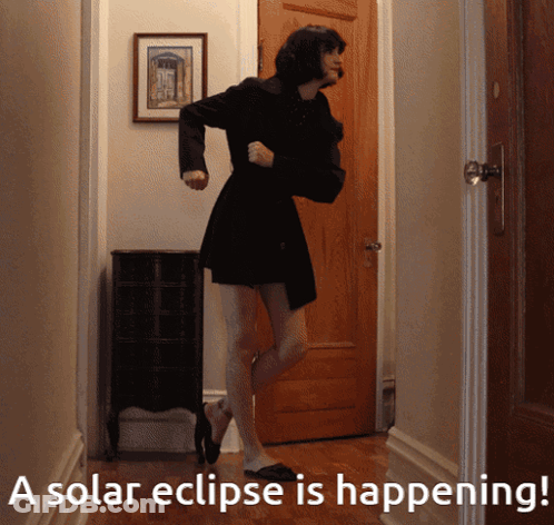 A Woman In A Black Dress Is Dancing In A Hallway With The Words A Solar Eclipse Is Happening Below Her GIF