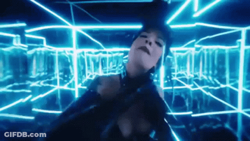 A Woman In A Black Dress Is Dancing In A Room With Blue Lights GIF