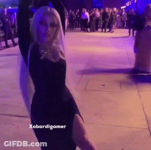 A Woman In A Black Dress Is Dancing In Front Of A Crowd And The Caption Says Xobardigmer GIF