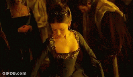A Woman In A Black Dress Is Dancing In Front Of A Crowd Of People In A Dark Room . GIF