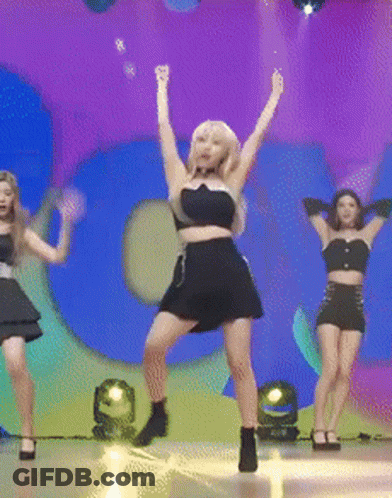 A Woman In A Black Dress Is Dancing On A Stage In Front Of A Large Number 5 GIF