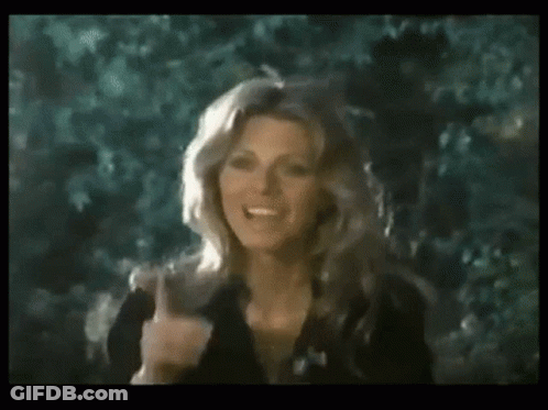 A Woman In A Black Dress Is Giving The Middle Finger While Standing In Front Of Trees . GIF
