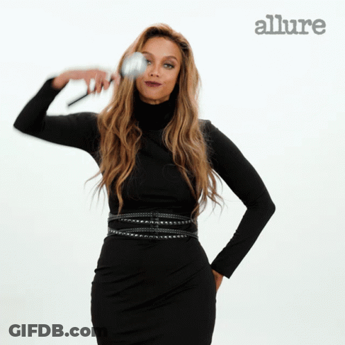 A Woman In A Black Dress Is Holding A Makeup Brush In Front Of An Allure Ad GIF