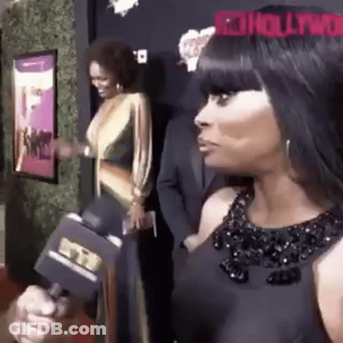 A Woman In A Black Dress Is Holding A Microphone In Her Hand . GIF