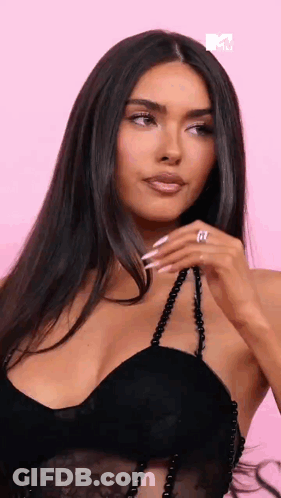A Woman In A Black Dress Is Holding A Necklace And Wearing A Ring . GIF